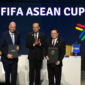 Trofi Piala ASEAN FIFA dengan latar stadion sepak bola.